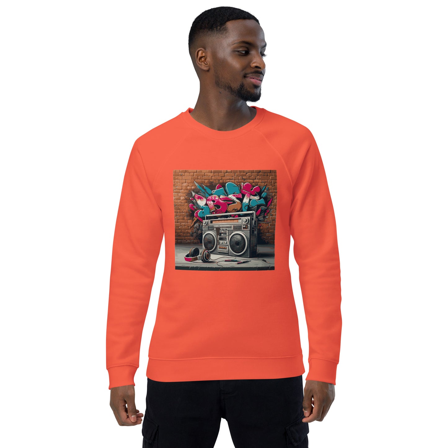 Männliches Model trägt Unisex-Bio-Raglan-Pullover mit Boombox-Design. Gebrannte Orange Farbe